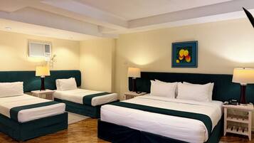 Une chambre d’hôtel avec deux lits, une petite table, une lampe, un tableau et un luminaire au plafond.