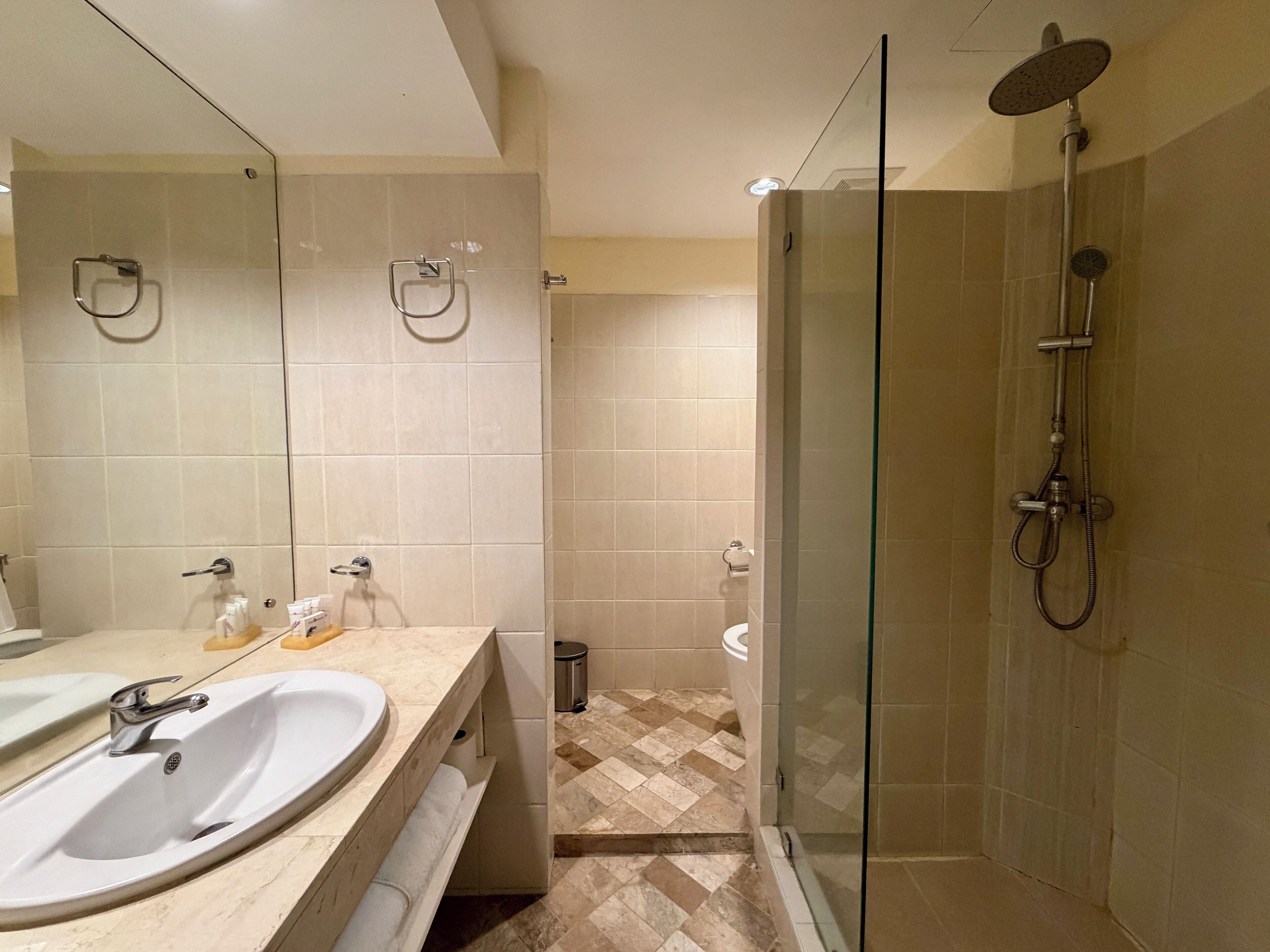 Un baño con dos lavamanos, una cabina de ducha de vidrio y suelo de baldosas.