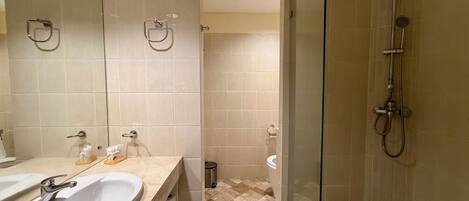 Un baño con dos lavamanos, una cabina de ducha de vidrio y suelo de baldosas.