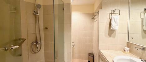 A bathroom with a glass-enclosed shower, a sink, and a mirror.