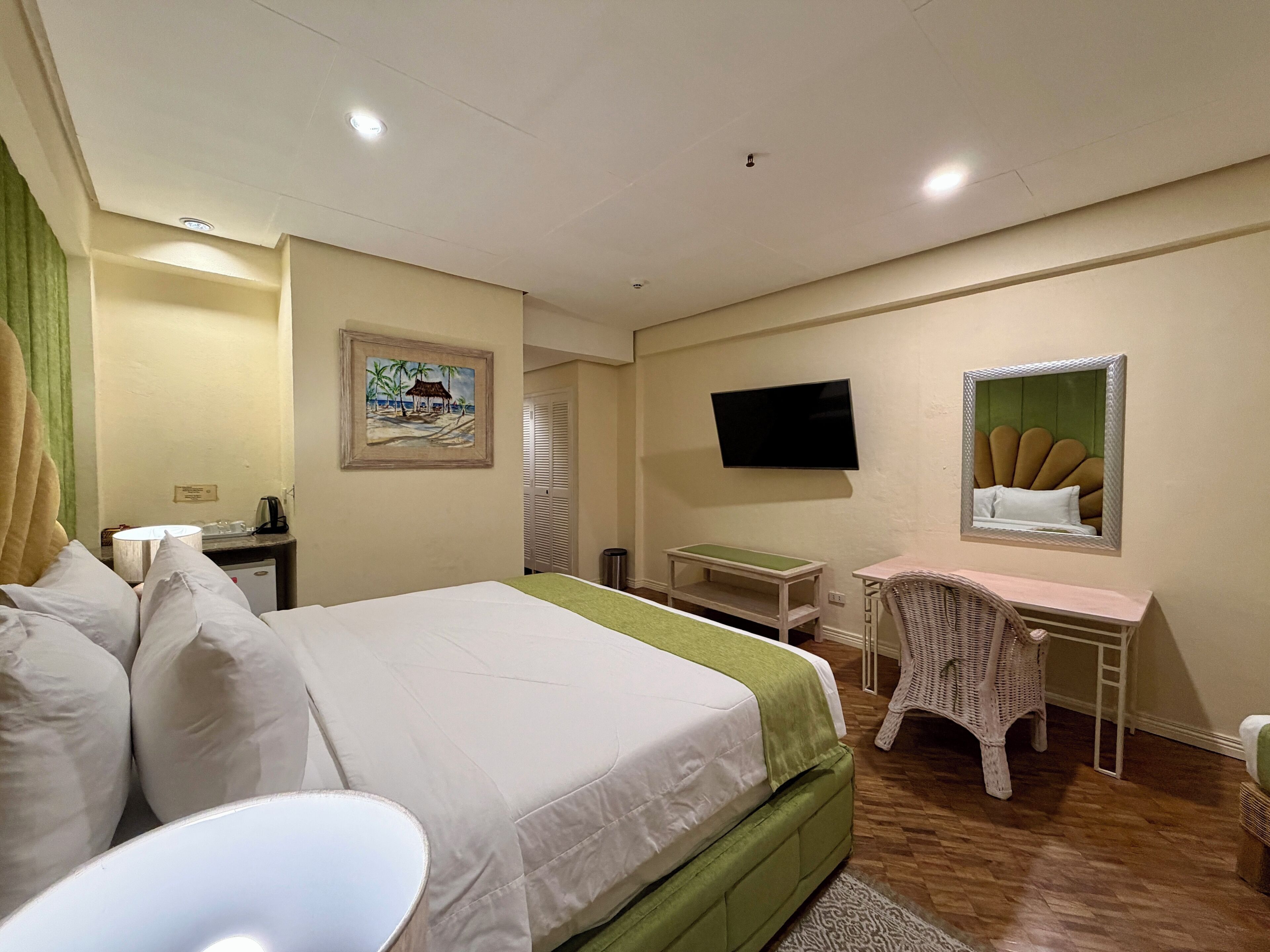 A hotel room with a bed, a desk, a television, and a mirror.