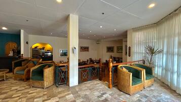 Un vestíbulo de hotel con muebles de mimbre, una estación de café y un comedor.