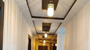 A hallway with a polished stone floor, white walls, and a ceiling with recessed lighting. - Hotel Bagga Kuteer (Haridwar)