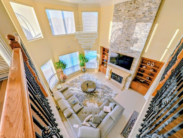 A spacious living room with a fireplace, a large TV, and a cozy seating area. - Villa Oak Lake Azure - Ultra Luxury Lakeview Oasis (Houston)