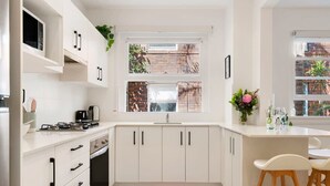 Une cuisine moderne avec des meubles blancs, une cuisinière à gaz, un four encastré et une fenêtre donnant sur l’extérieur.