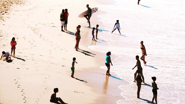 Une plage bondée où l’on voit des gens se promener, bronzer et jouer.