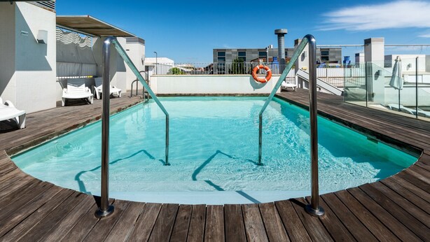 En pool med ett trädäck, metallräcken och en livboj.