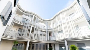 En atriumgård i flera våningar med balkonger, stora fönster och krukväxter.