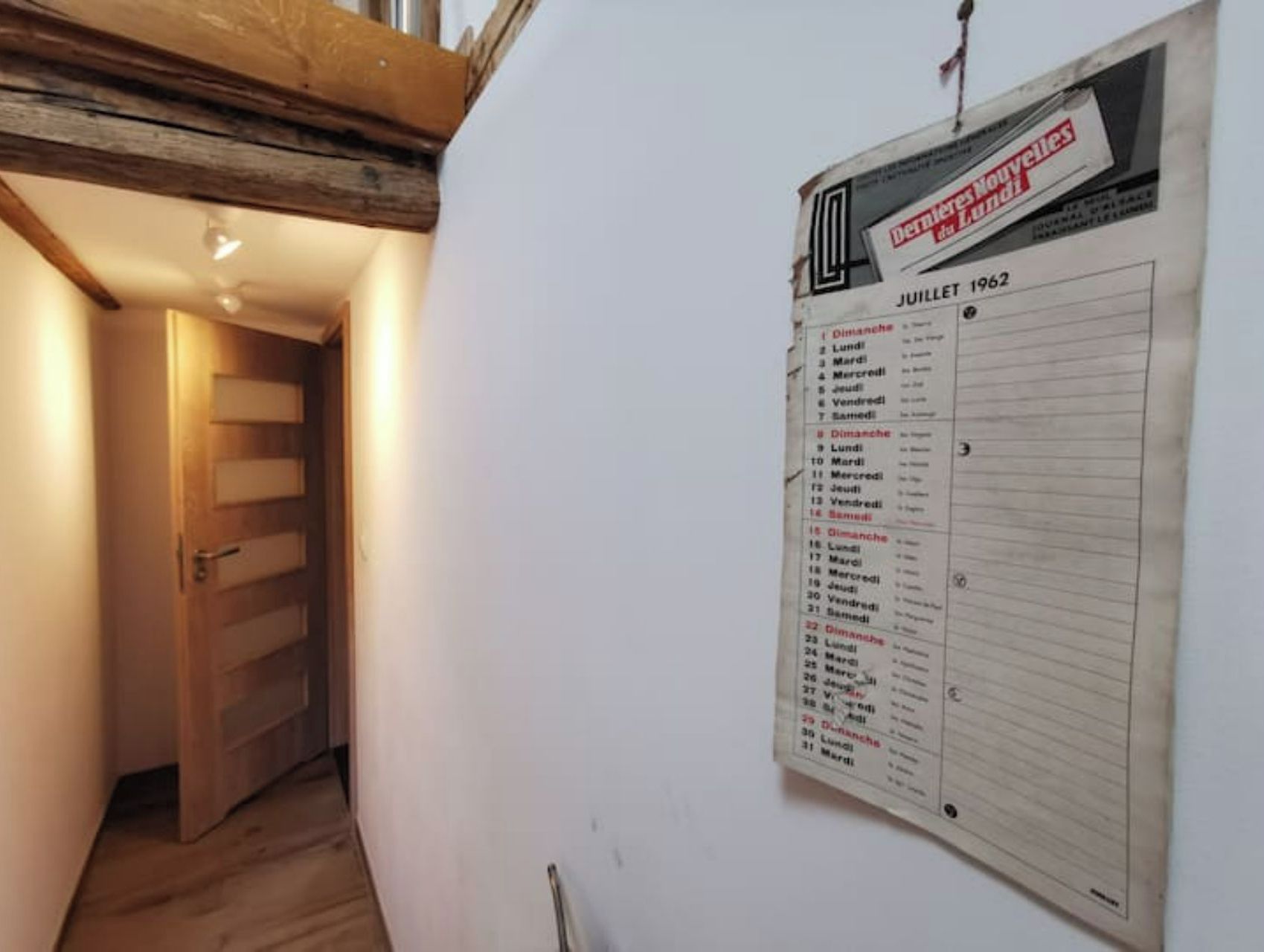 Un pasillo con una puerta de madera y un tablón de anuncios que muestra una lista de fechas y eventos.