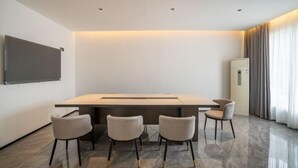 A modern hotel room with a large flat-screen TV mounted on the wall, a central dining table with four chairs, a built-in air conditioning unit, and a large window with curtains. - BoYea Hotel (Zhuhai Pingsha Ocean Spring Resort) (Zhuhai)