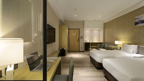 A hotel room with a bed, desk, chair, TV, and a small kitchenette. - Joyfultel (Taoyuan City)