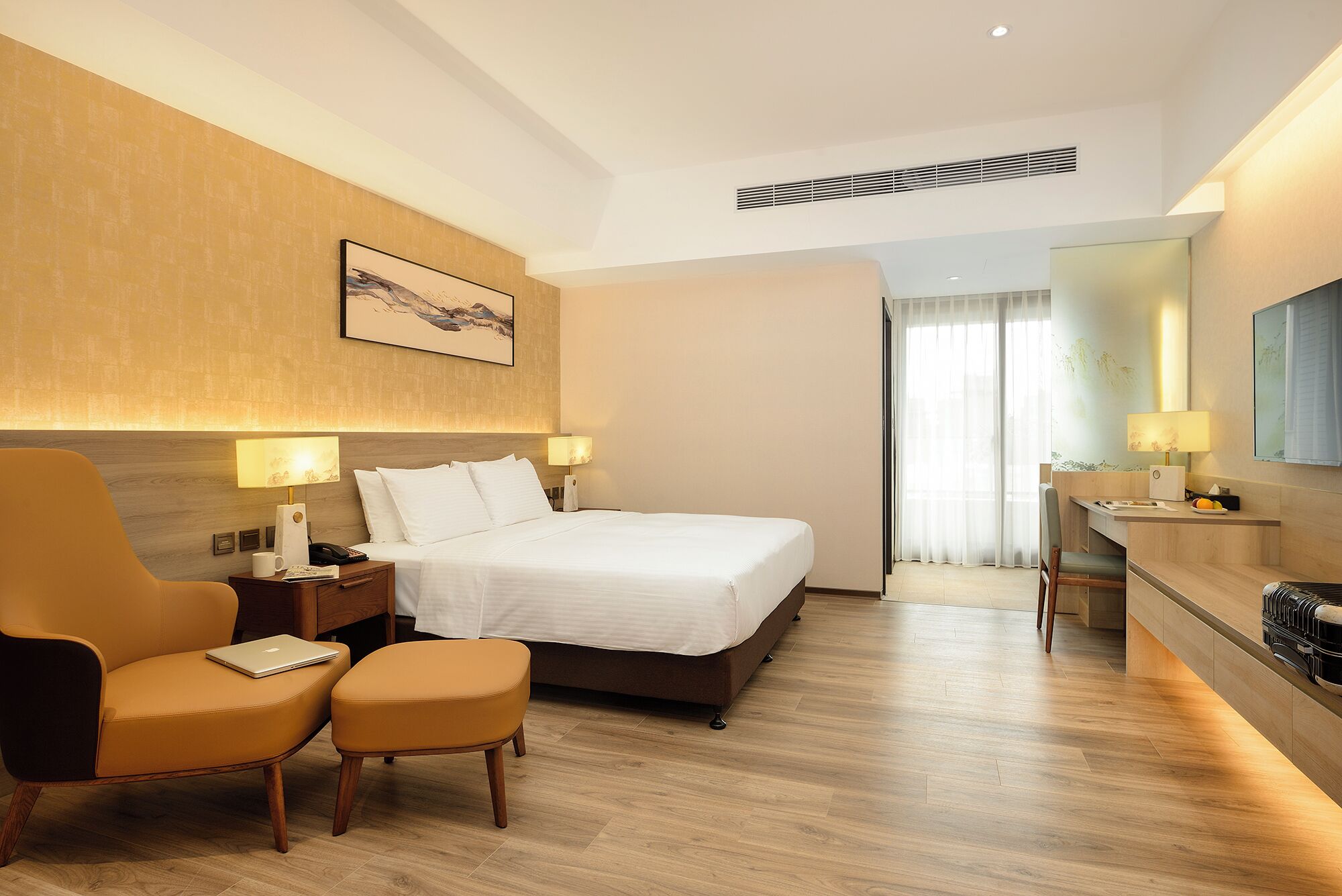 Ein Hotelzimmer mit Bett, Schreibtisch, Stuhl und einem kleinen Hocker.