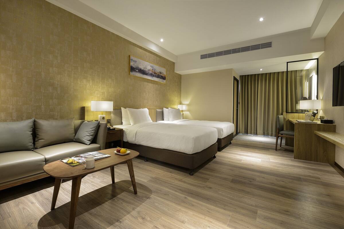 Una habitación de hotel con una cama, un sofá, un escritorio y una silla.
