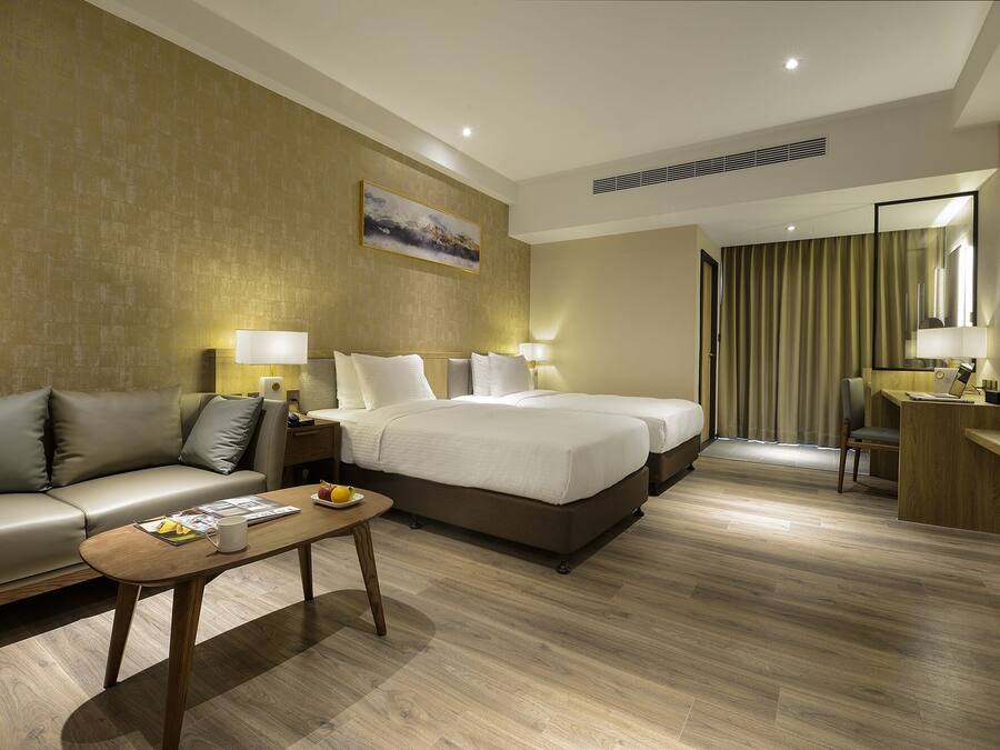 A hotel room with a bed, a sofa, a desk, and a chair.