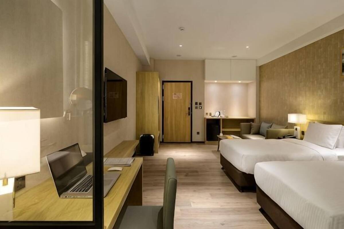 Una habitación de hotel con una cama, un escritorio con una computadora portátil, un televisor y un baño.