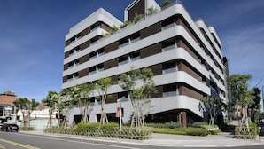 A modern multi-story building with a unique architectural design, featuring balconies and a mix of glass and concrete materials. - Joyfultel (Taoyuan City)
