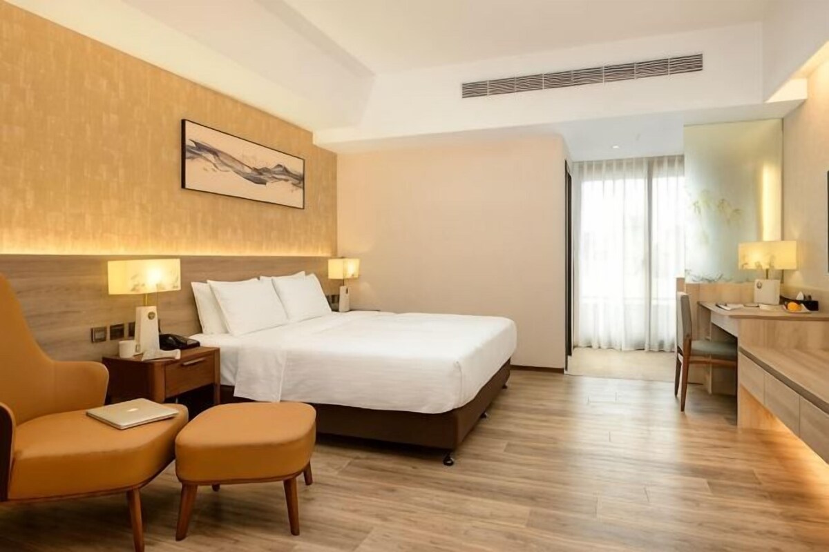 Une chambre d’hôtel comprenant un lit, des tables de chevet, une chaise, un bureau et un miroir.