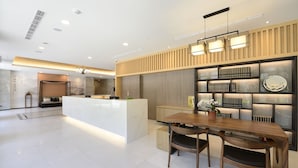 A modern hotel lobby with a reception desk, seating area, and a bookshelf with books. - Joyfultel (Taoyuan City)