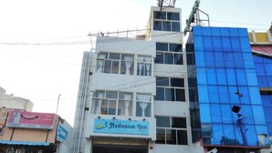 A building with a sign for 'Nadanam Inn' and a blue glass facade. - Nadanam Inn (Puducherry)