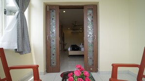 A hotel room with a bed, a ceiling fan, and a bathroom visible through an open door. - Nadanam Inn (Puducherry)