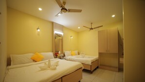 A hotel room with two beds, a ceiling fan, and a large mirror. - Nadanam Inn (Puducherry)
