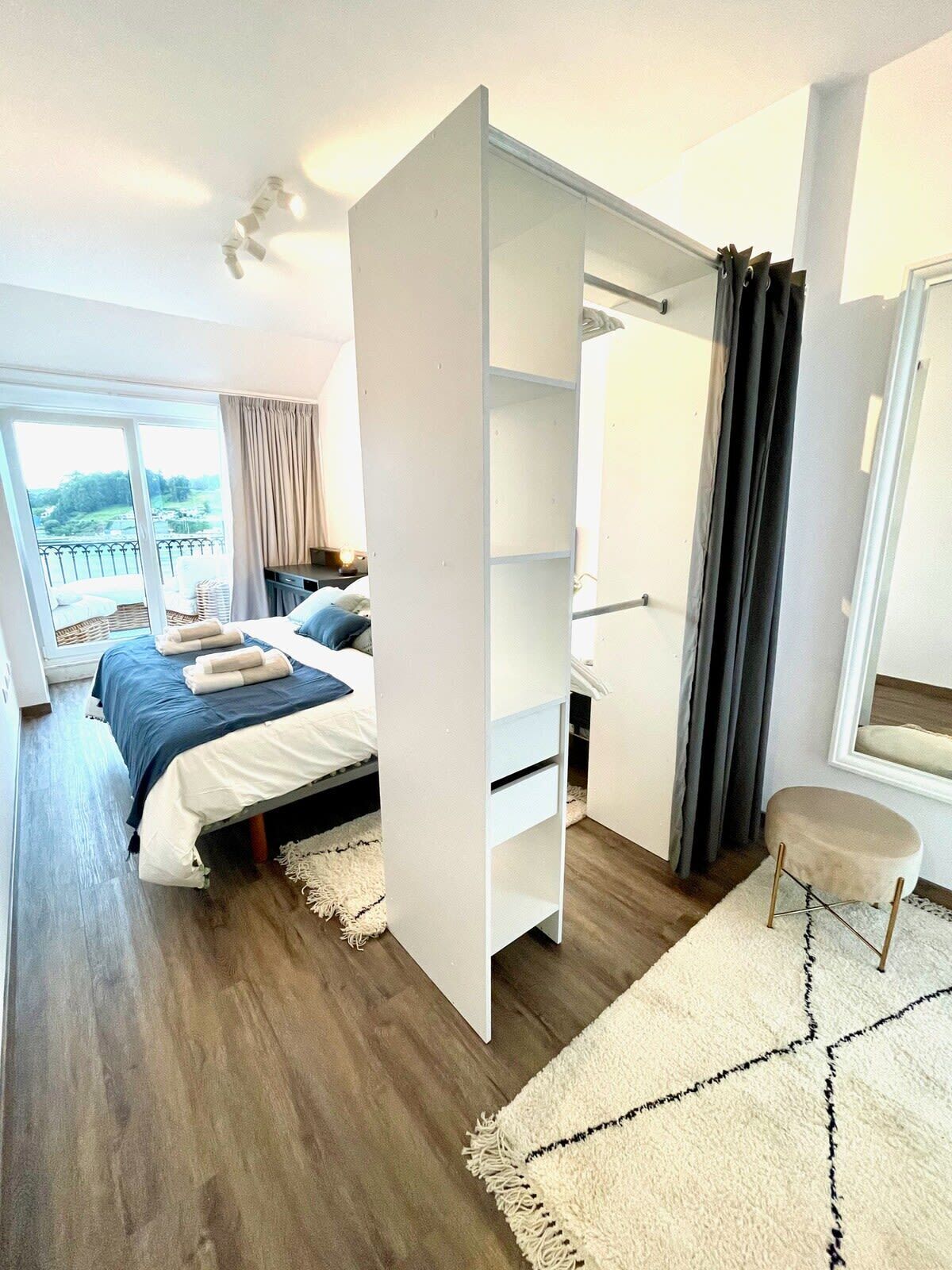 Ein modernes Schlafzimmer mit einem großen Bett, einem Schreibtisch und Blick auf einen Balkon.
