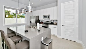 A modern kitchen with white cabinets, stainless steel appliances, and a central island with seating.