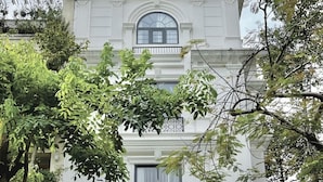 A grand building with a classic architectural style, featuring a prominent entrance with a large glass door and a sign reading "RACHEL SERVICED APARTMENT."
