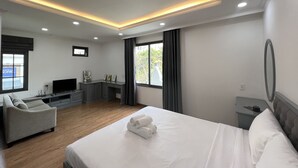 A modern hotel room with a large bed, a sofa, a desk, and a television.