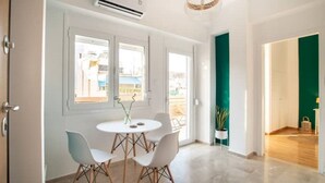 Una habitación moderna con una mesa redonda y cuatro sillas, ventanas amplias y una pared de acento verde.