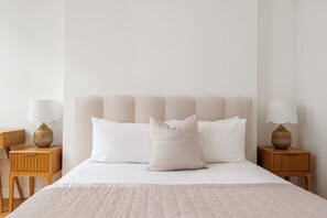 A minimalist bedroom with a large bed, two nightstands, and a headboard.