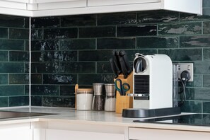 A kitchen with a coffee machine, a knife block, and a spice jar.