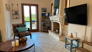 A living room with a fireplace, a TV mounted on the wall, a sofa, and a dining table. - Relax with the whole family at this peaceful place to stay. (tzemi)