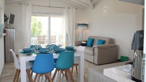 A dining area with a table set for four, a sofa, and a coffee machine. - R House (Budoni)
