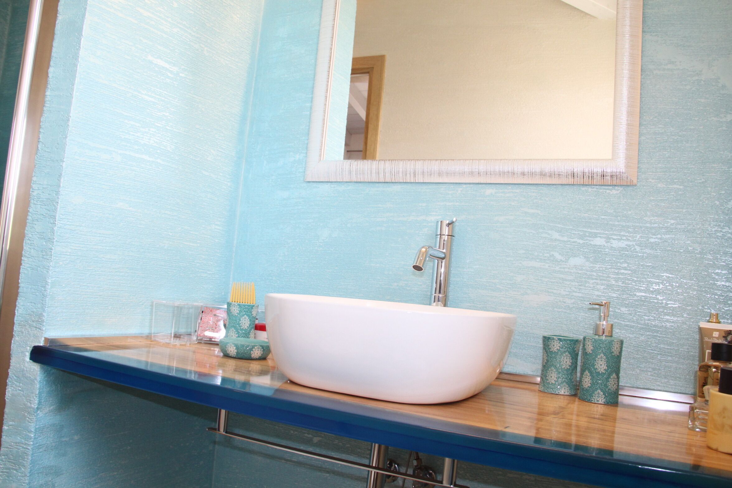 A bathroom with a white sink, blue countertop, and a mirror above the sink.