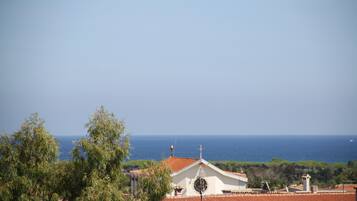 Une vue sur la côte, avec un bâtiment doté d’un toit recouvert de tuiles rouges et surmonté d’une croix, le tout entouré de verdure.
