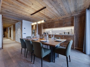 Une cuisine moderne avec des meubles en bois, un coin repas avec une longue table et des chaises, et un couloir avec un plancher et des murs en bois.