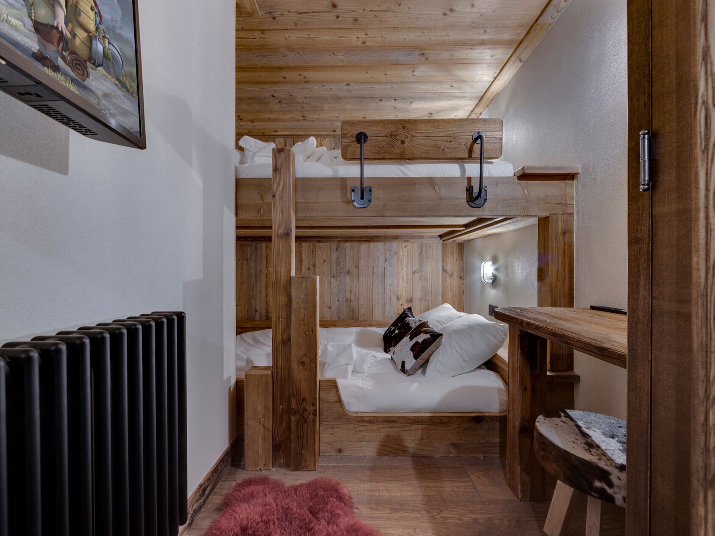 Une chambre avec un lit superposé, des murs en bois et un radiateur.