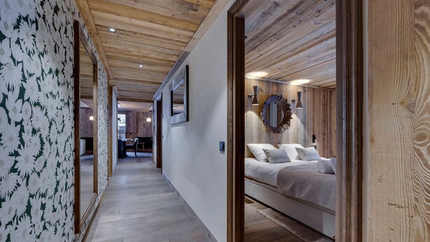 A bedroom with a wooden ceiling, a bed with white bedding, and a mirror on the wall. - Spacious apartment near slopes with jacuzzi and parking (Montvalezan-La Rosière)