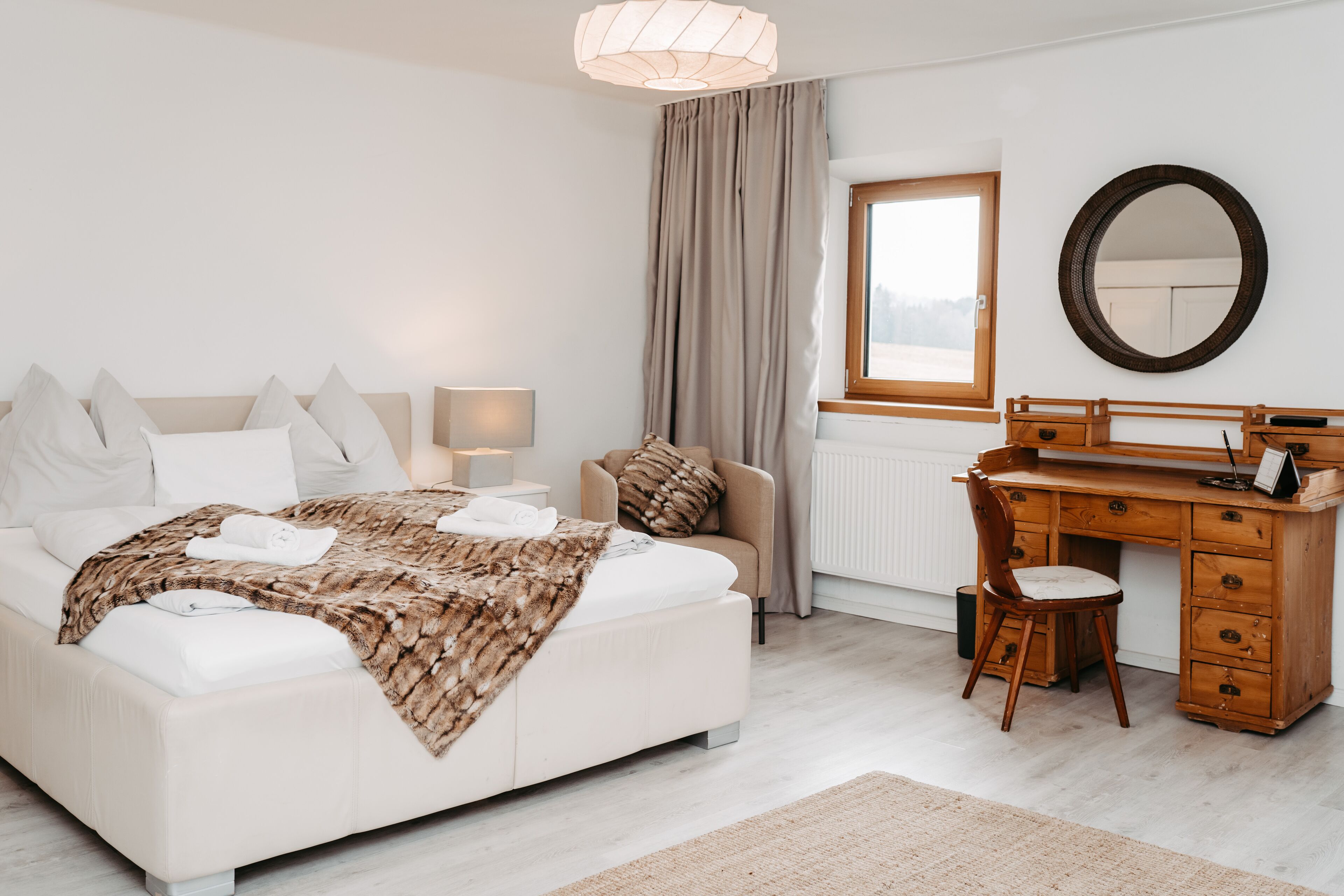 Une chambre à coucher comprenant un lit, une table de chevet, une lampe, une chaise, un bureau et un miroir.