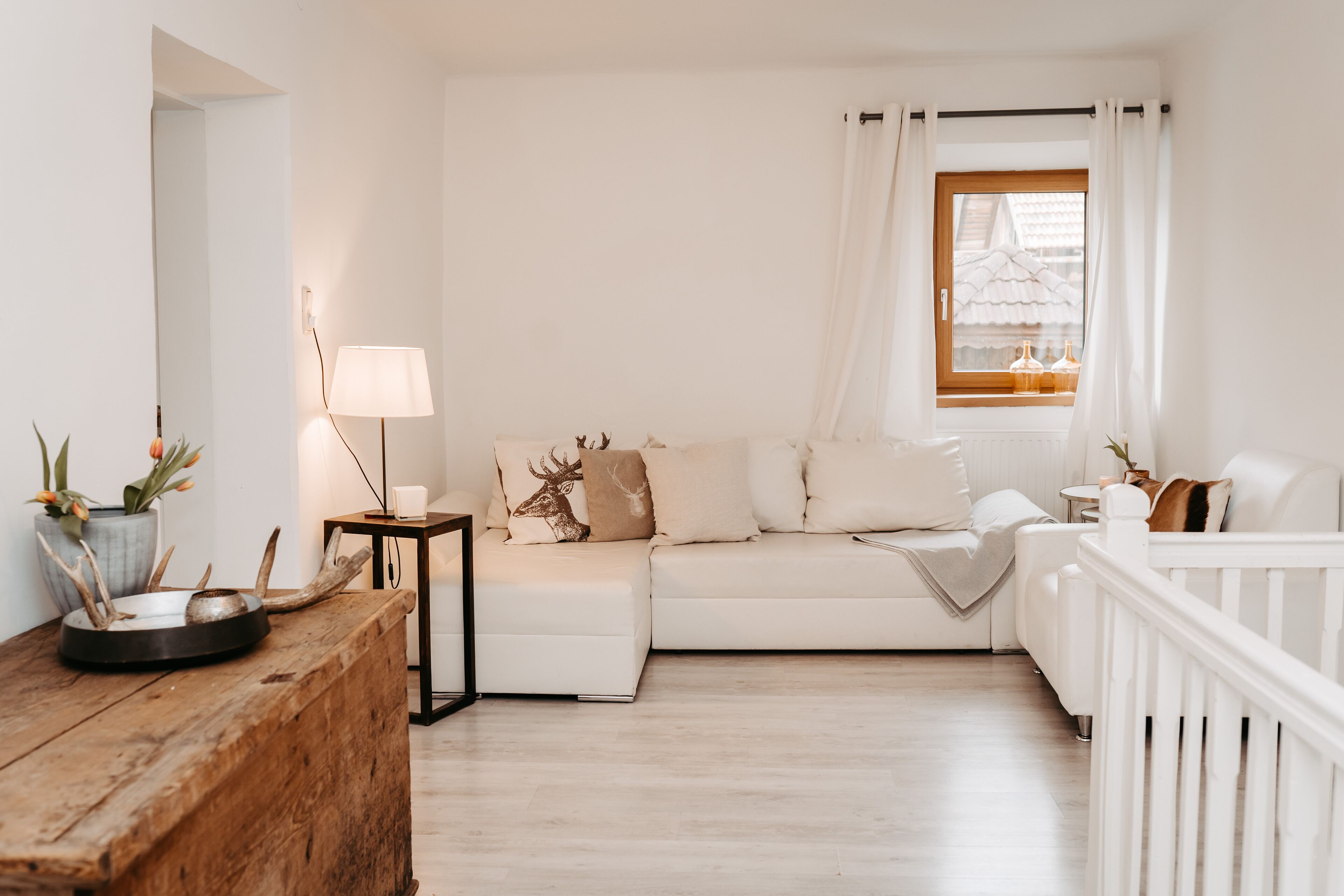 A cozy living room with a white sofa, a wooden coffee table, and a lamp.