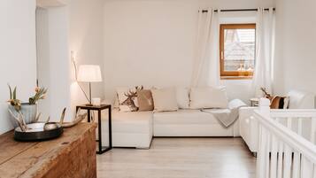 A cozy living room with a white sofa, a wooden coffee table, and a lamp.