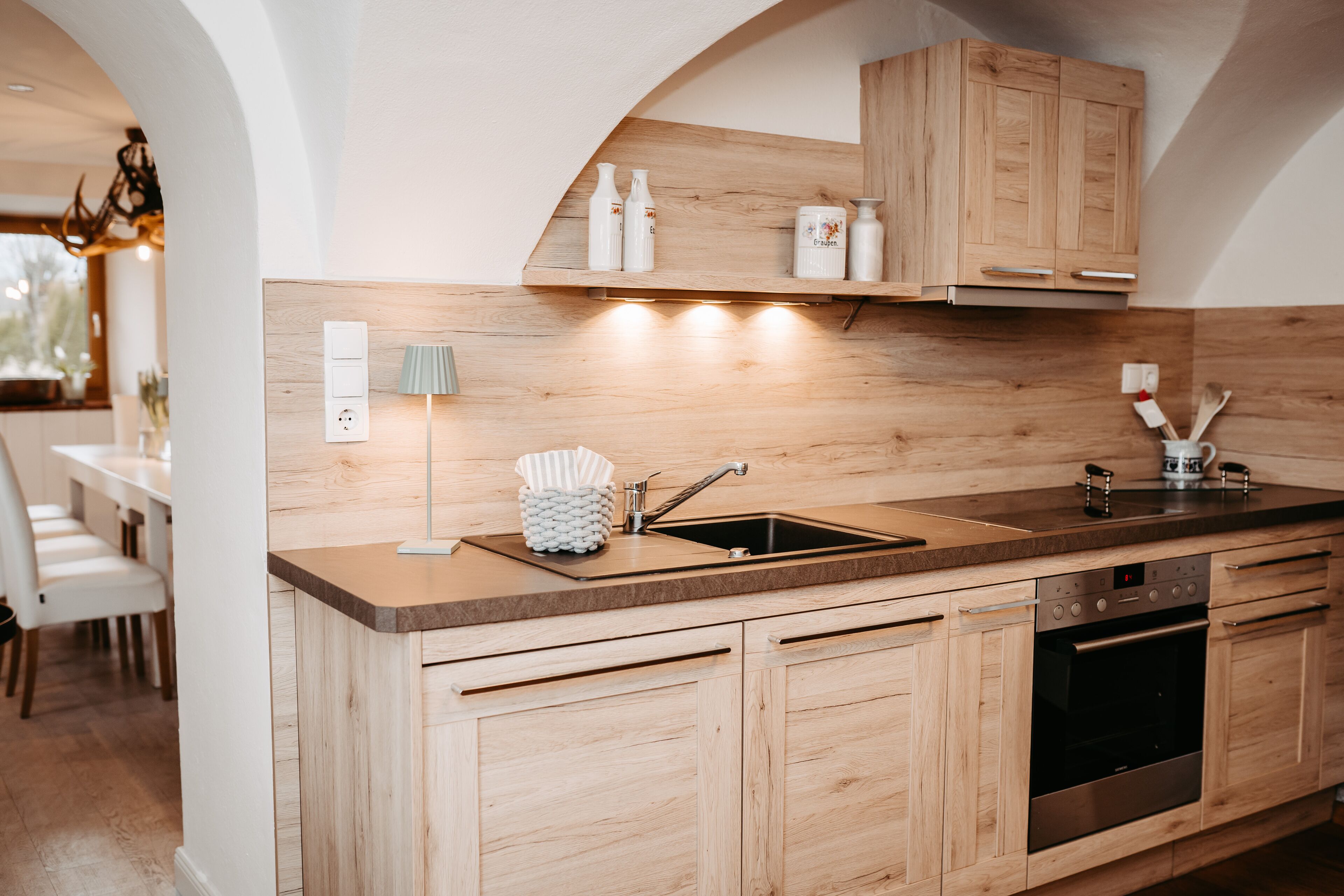 Eine moderne Küche mit Holzschränken, einem Edelstahlbackofen und einer eingebauten Spüle.