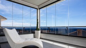 Un balcone moderno con una sedia imbottita bianca, un tappeto bianco e una pianta in vaso.