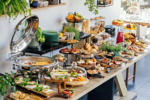 Ein reichhaltiges Buffet mit verschiedenen Speisen, darunter Salate, Sandwiches und Gebäck.