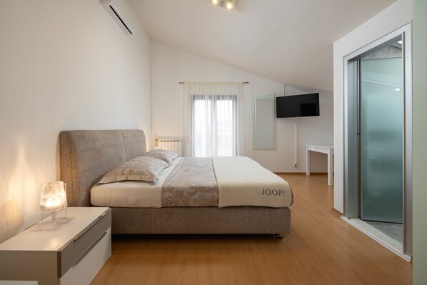 Ein Schlafzimmer mit Bett, Nachttisch und einem an der Wand befestigten Fernseher.