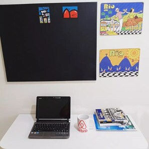 Un ordinateur portable sur une table, avec une tasse blanche et un livre.