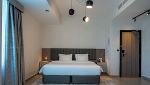 Ein modernes Schlafzimmer mit einem großen Bett, Nachttischen, einem Kleiderschrank und einer Deckenleuchte.