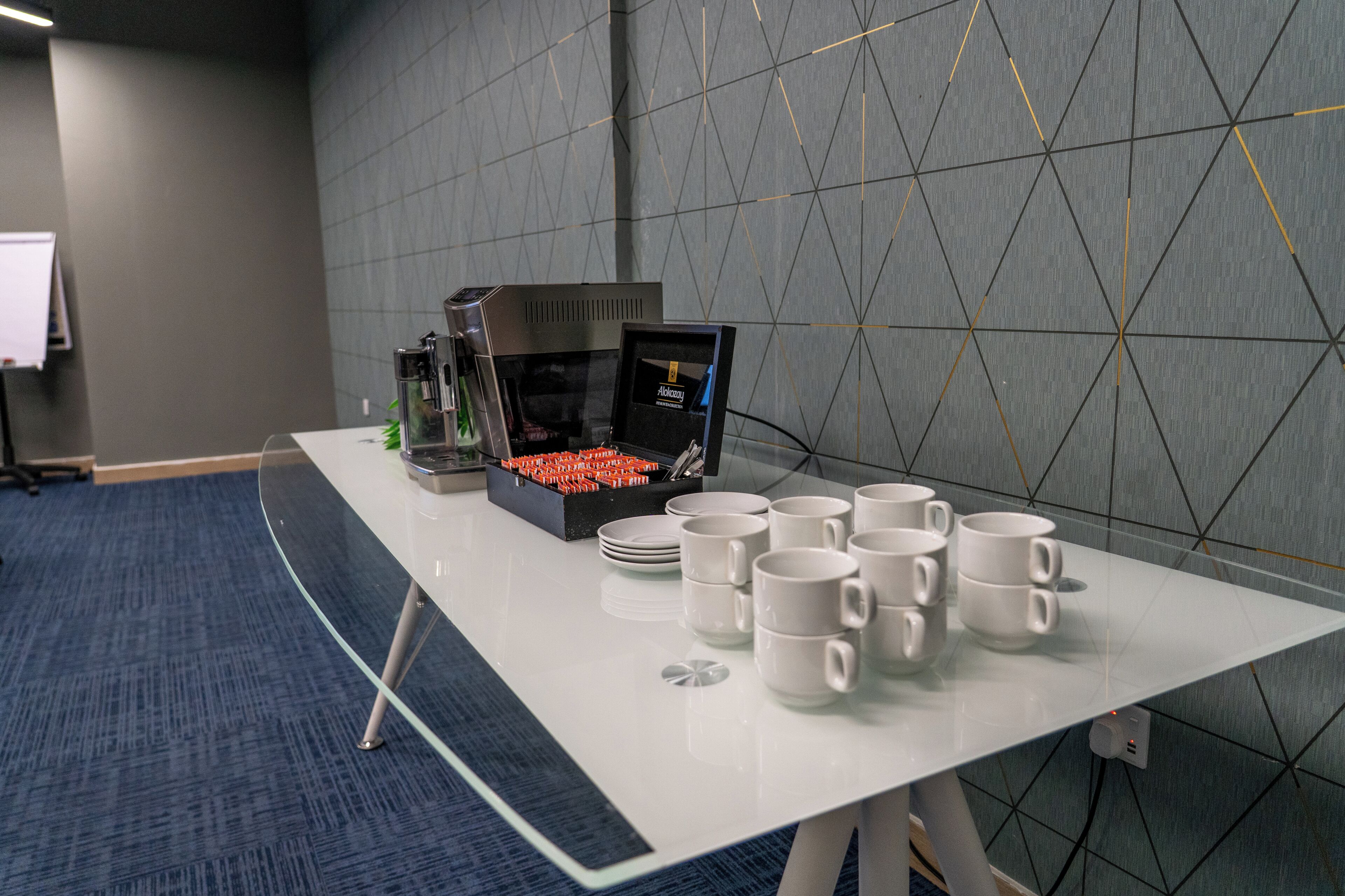 Une table de conférence avec une machine à café, des assiettes et des tasses.