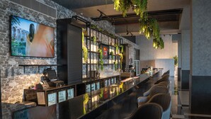 Eine moderne Bar mit einer langen Theke, Barhocker und einem an einer Ziegelwand befestigten Fernseher.